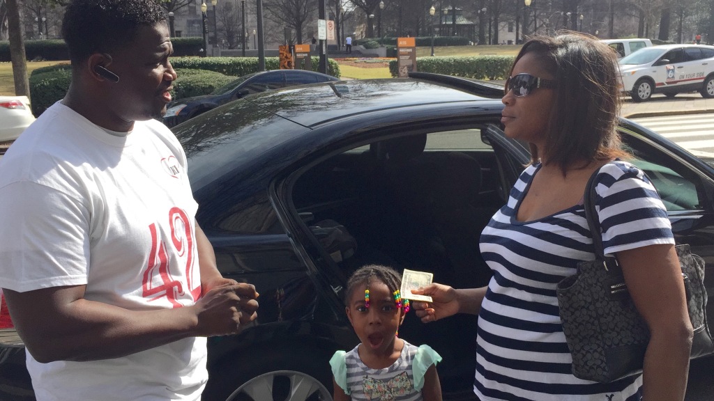 Sherman Collins Jr. hands two, $5 bills to citizen and her daughter, telling them that lunch is on him. Photo by: Chanda Temple 