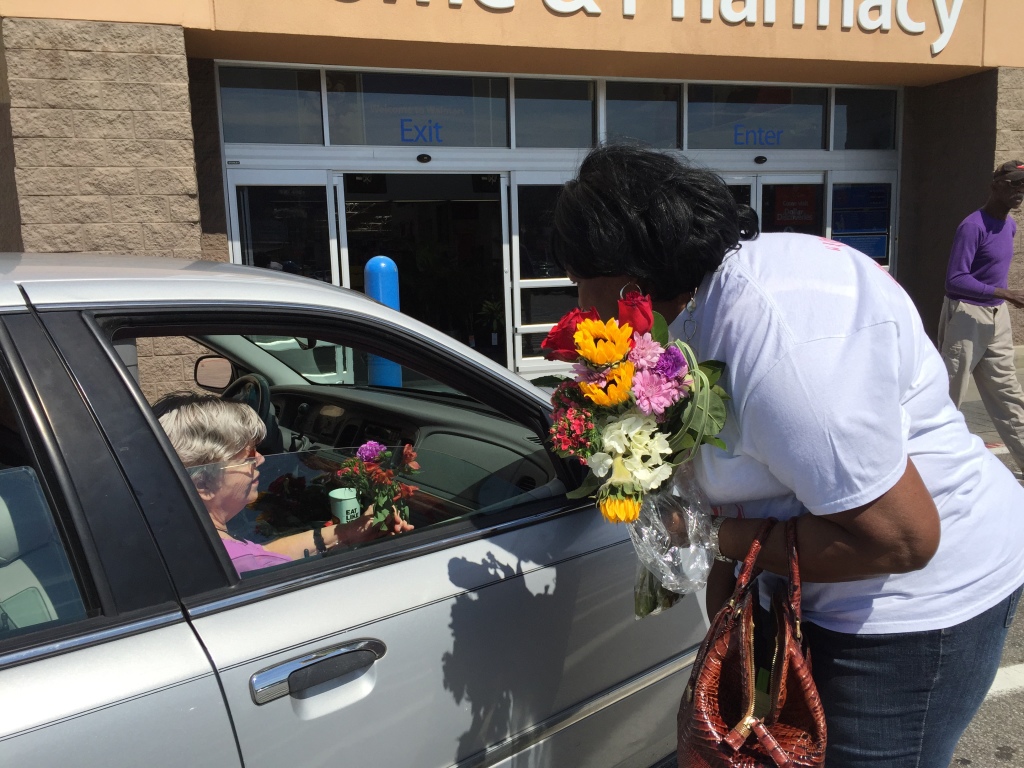 Mary Bethune, Katrina Collins' daughter, passes out flowers to strangers in the Walmart Roebuck parking lot. (Photo by: Chanda Temple) 